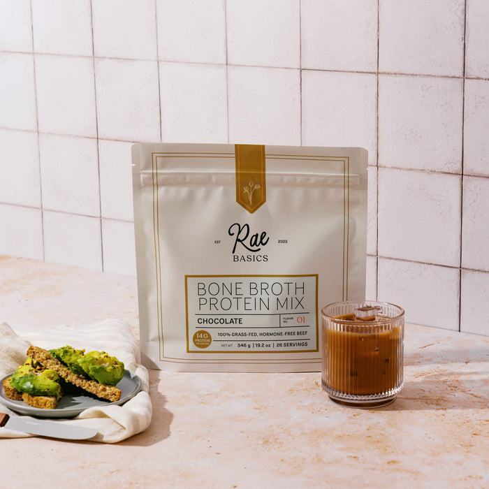 Bag of Rae Basics Classic Chocolate Bone Broth Protein Mix with avocado toast and an iced chocolate drink